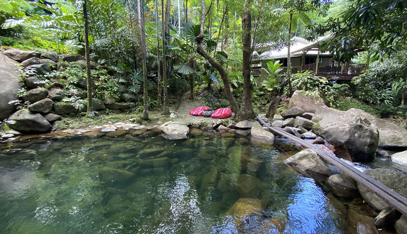 Relaxing Creek Deck at Daintree Secrets Overhead view of relaxing bean bags by a private swimming hole with a wooden footbridge over the creek