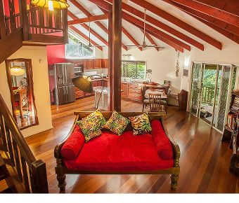 Daintree Luxury Holiday Rental Open Plan Living Open plan living room with high ceilings, fully equipped kitchen, dining area, and sliding doors to the veranda deck.